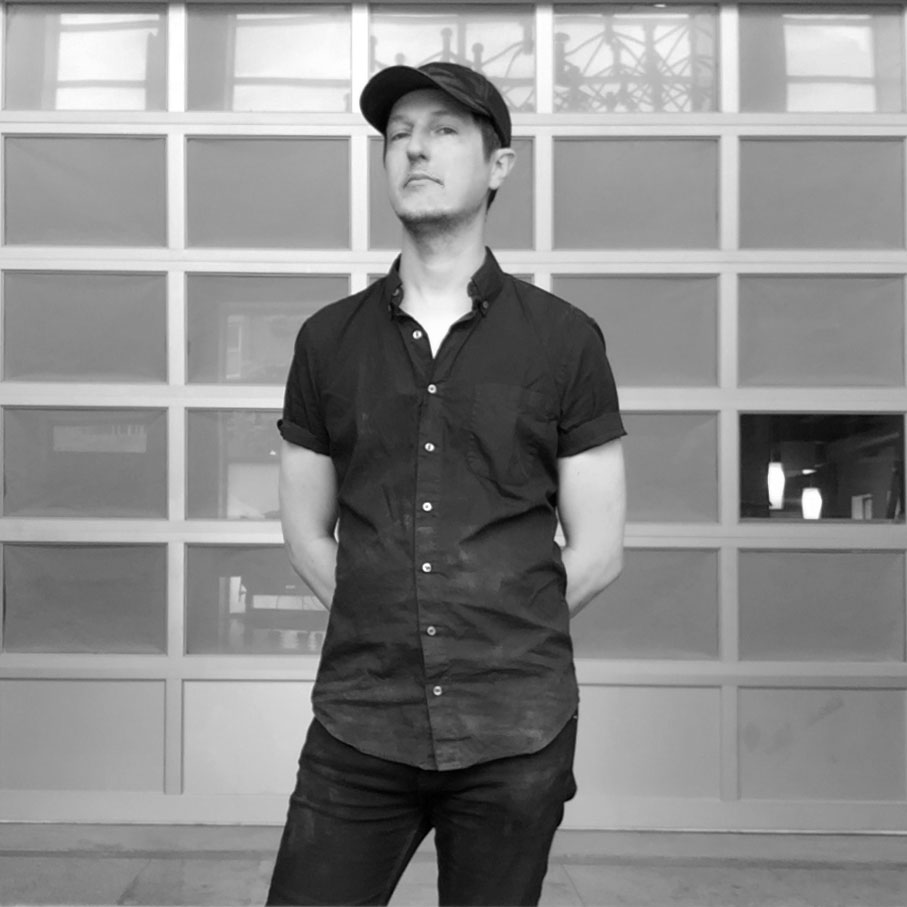 Black and white photo of a man standing with his arms behind his back