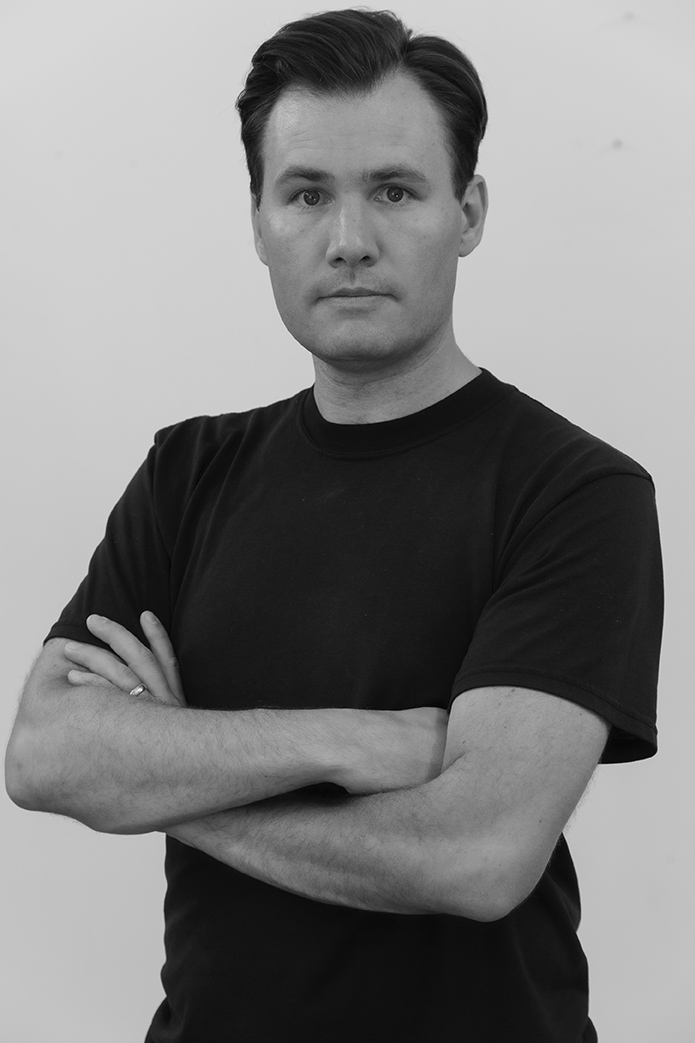 Black and white photograph of a man with his arms crossed and looking at the camera