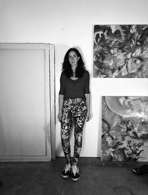 Black and white photograph of a woman standing next to abstract paintings
