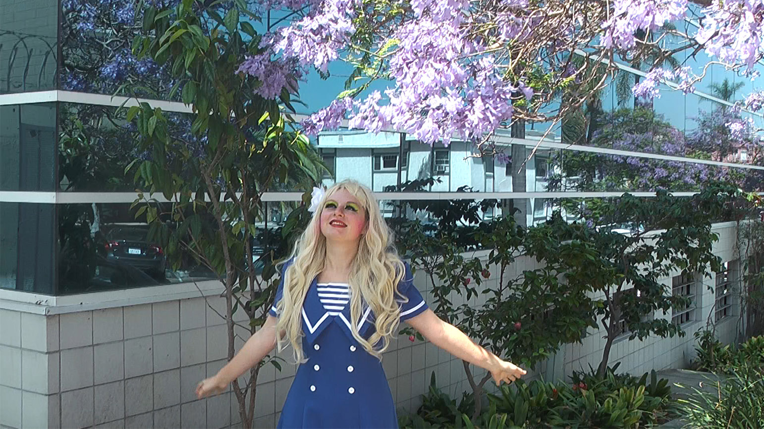Still from video "And They Wonder Why We're Romantics" showing a woman looking up at a flowery tree