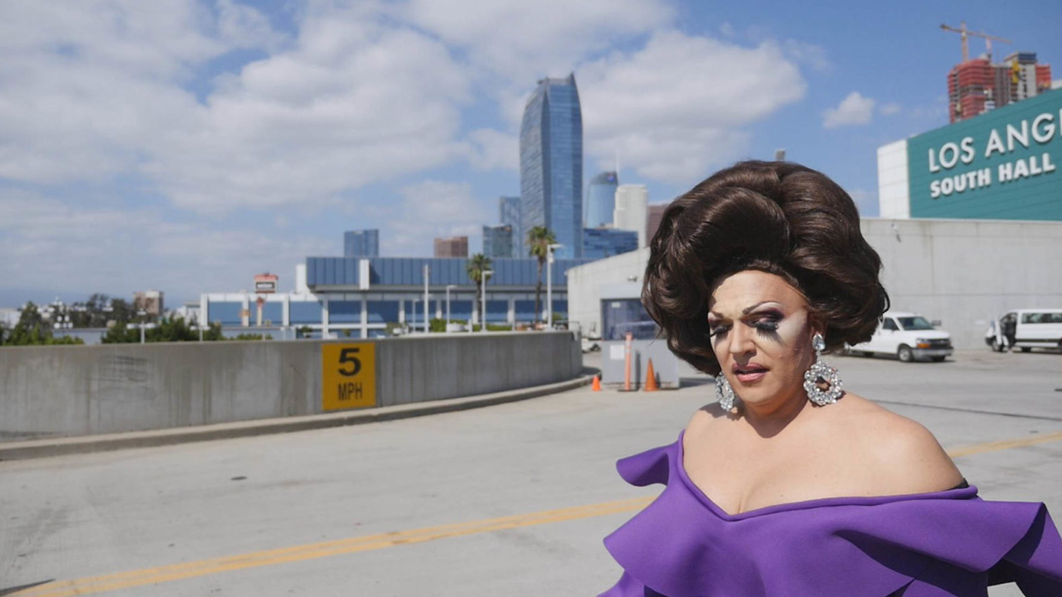 Still from the documentary "Workhorse Queen" showing a drag queen with a city skyline in the background