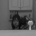 Black and white photograph of Diane Lee taken in a bathroom mirror