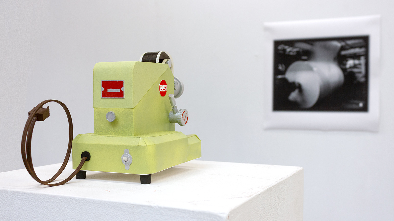 Paper sculpture of a film projector facing a paper replica of a screen
