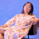Image of Nana Cheon leaning back in a chair against a blue background